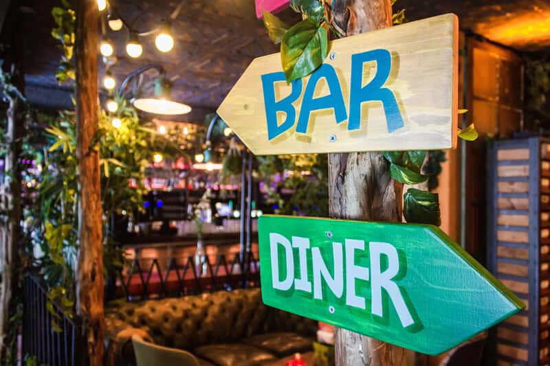 An image of bar and diner directional signage (arrows pointing opposite ways).